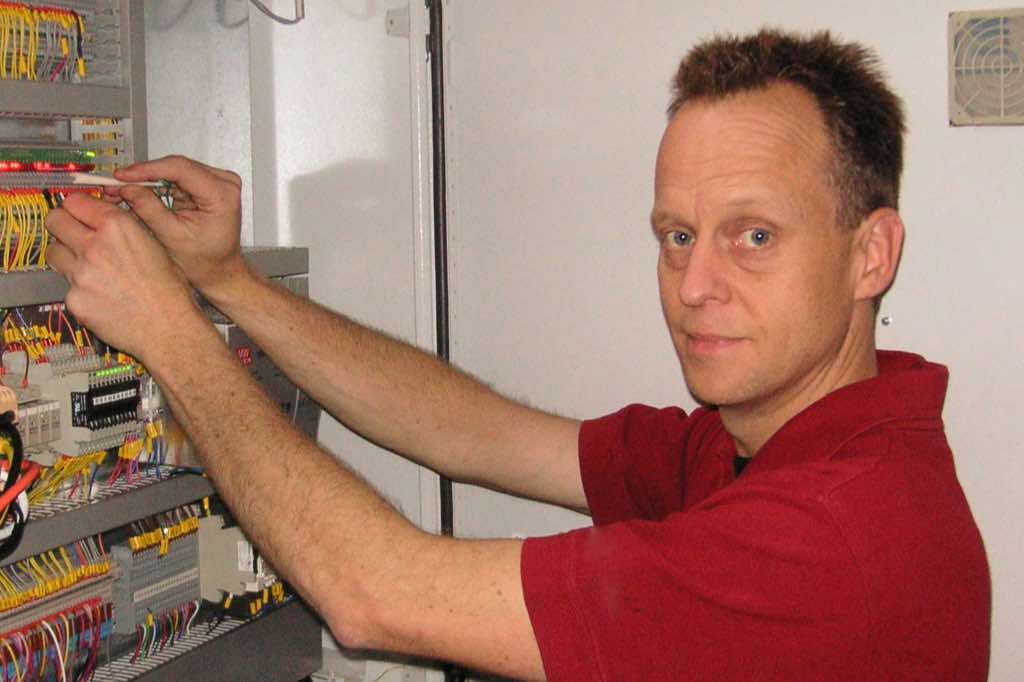 man står arbetandes vid elskåp